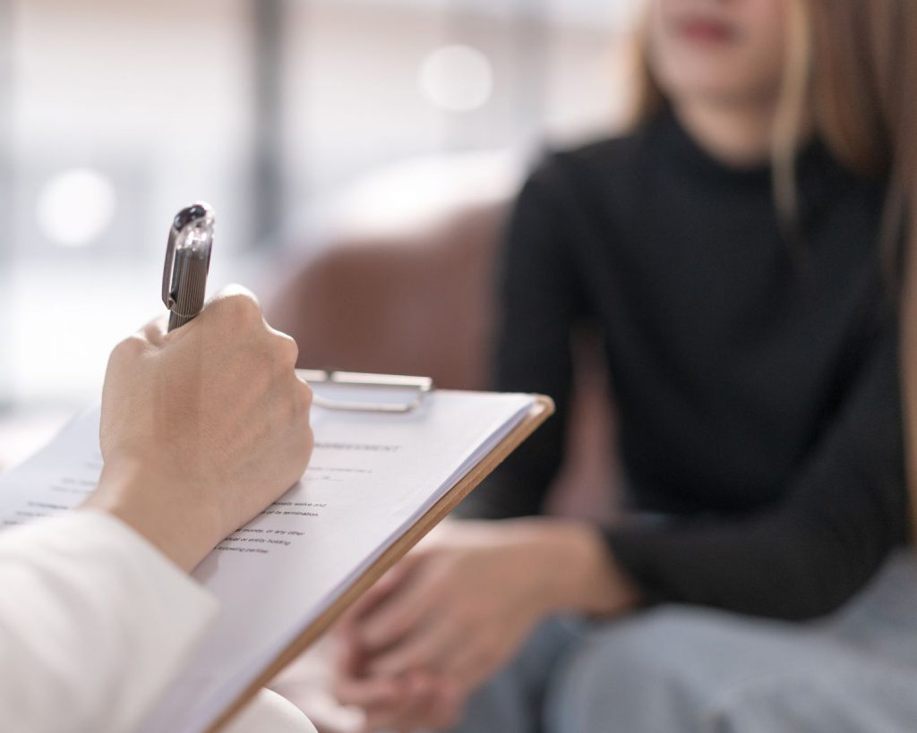 image of a counselor writing on a clipboard while having a counseling session with a student