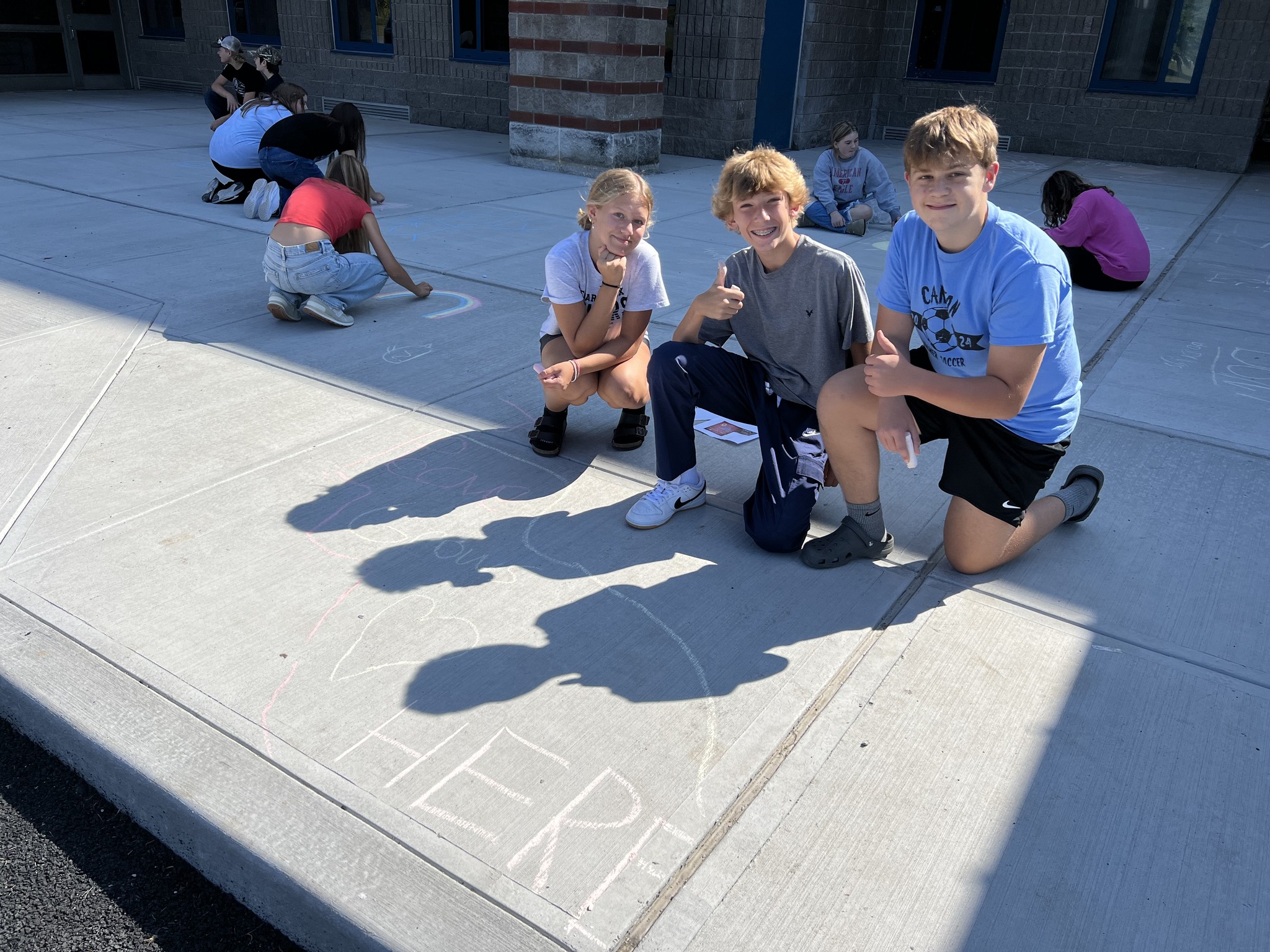 students drawing on sidewalk with chalk, students posing with their work