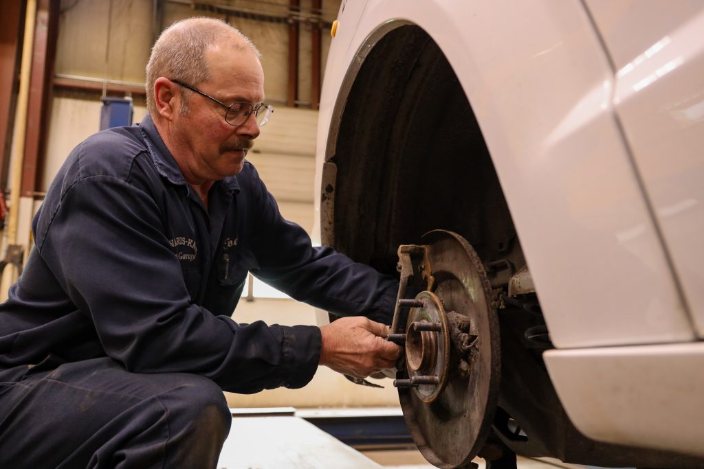 A mechanic working on the brakes of a vehicle in a garage