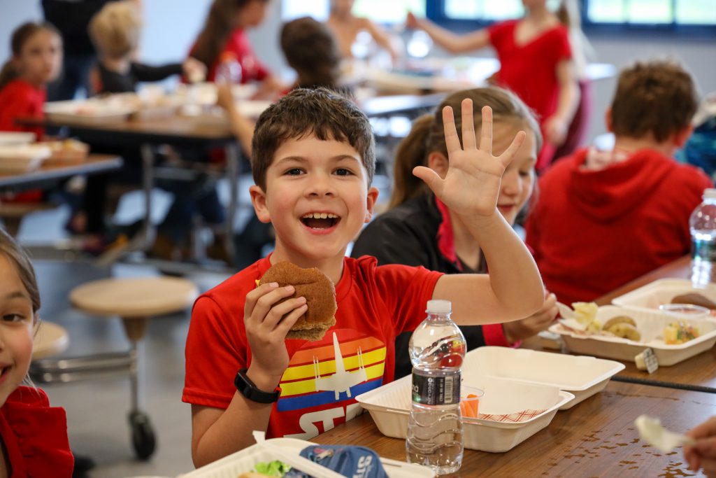 Student holding burger at a lunch table