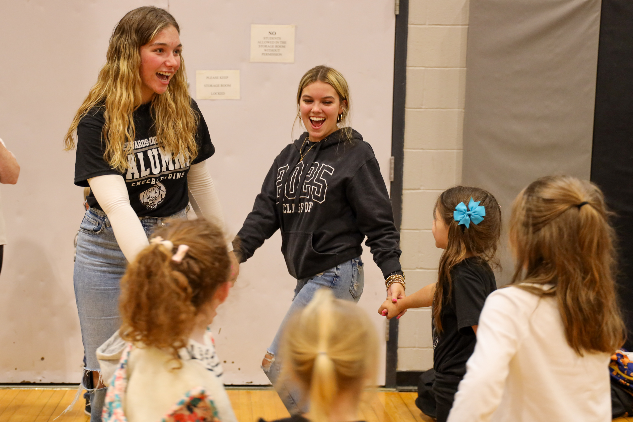 Two students holding hands with younger students in a circle