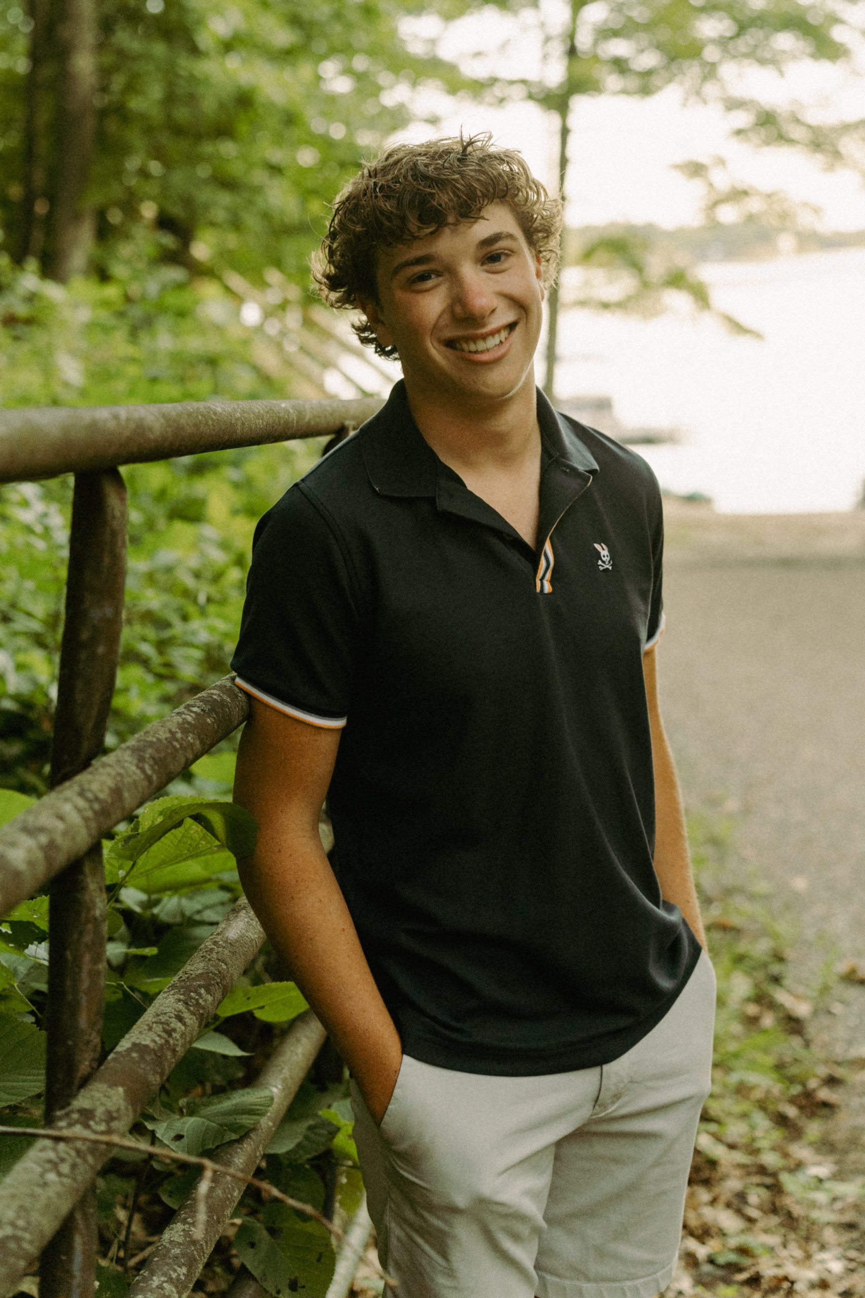 A student standing in front of a fence near a body of water