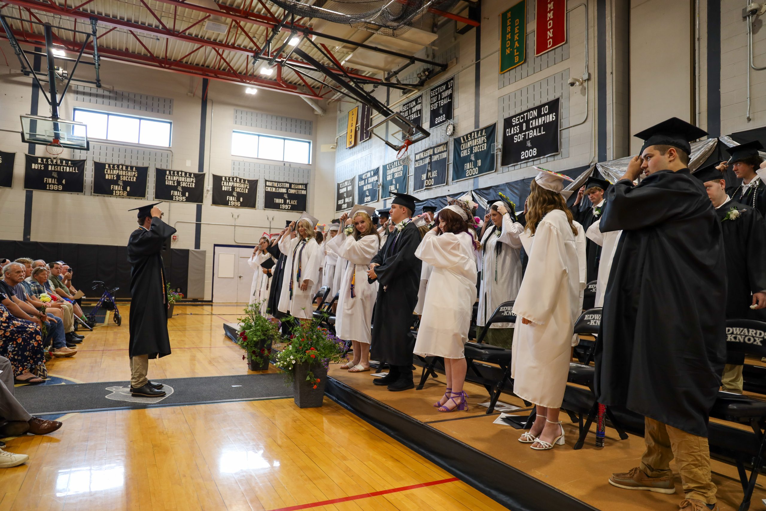 Students wearing caps and gowns inside a gymnasium