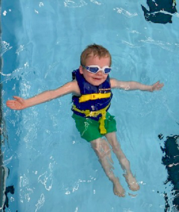 A student wearing a life jacket floating in pool