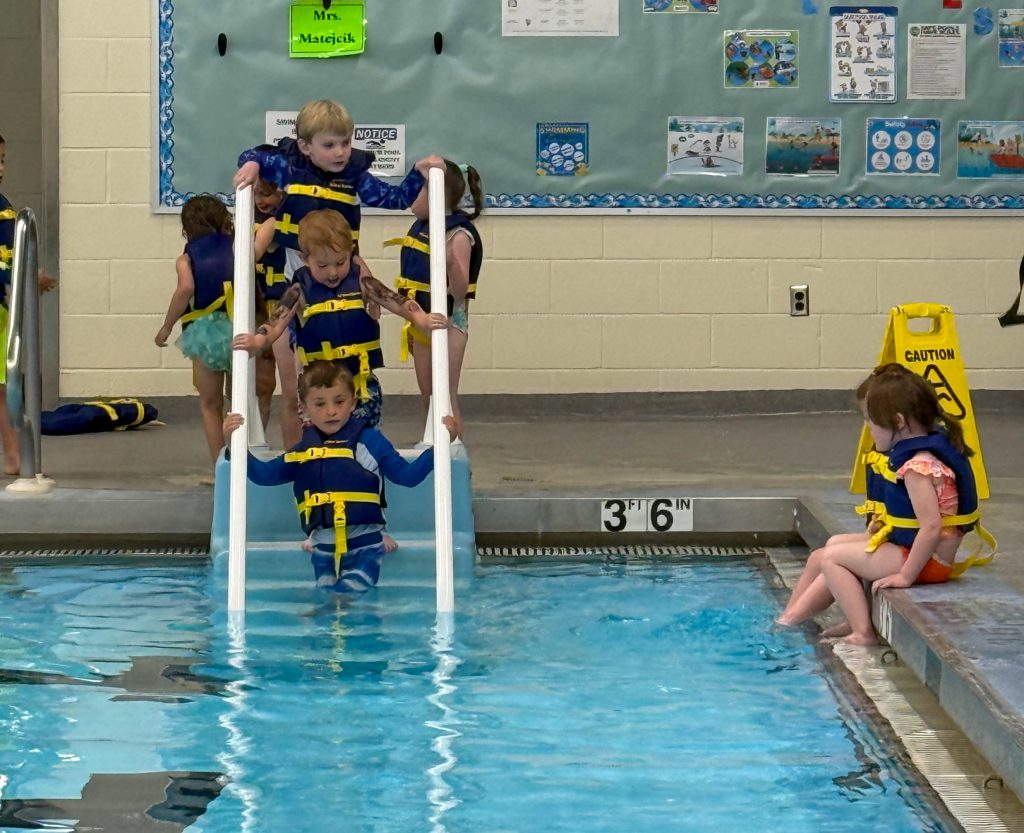 Several students using stairs to enter a pool