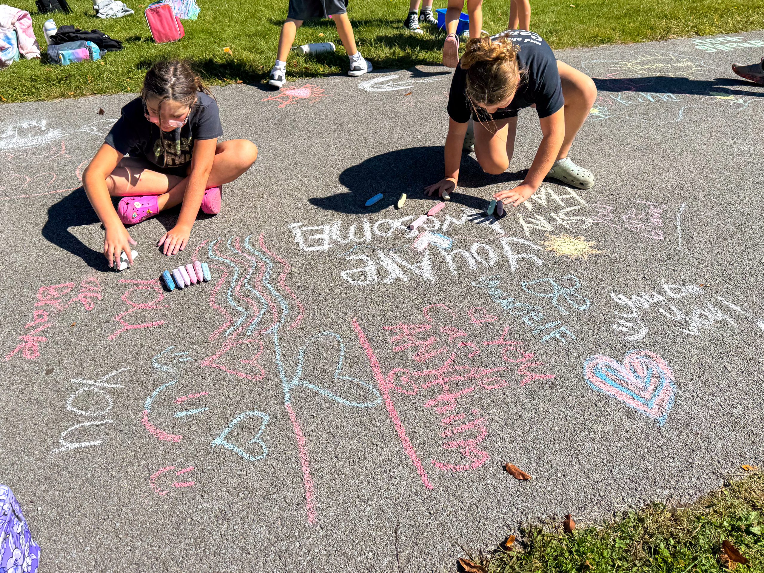 Two students drawing on pavement with chalk