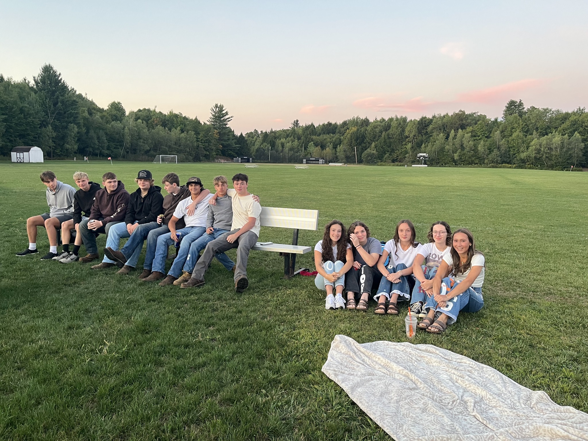 Students sitting together on a bench and on the ground