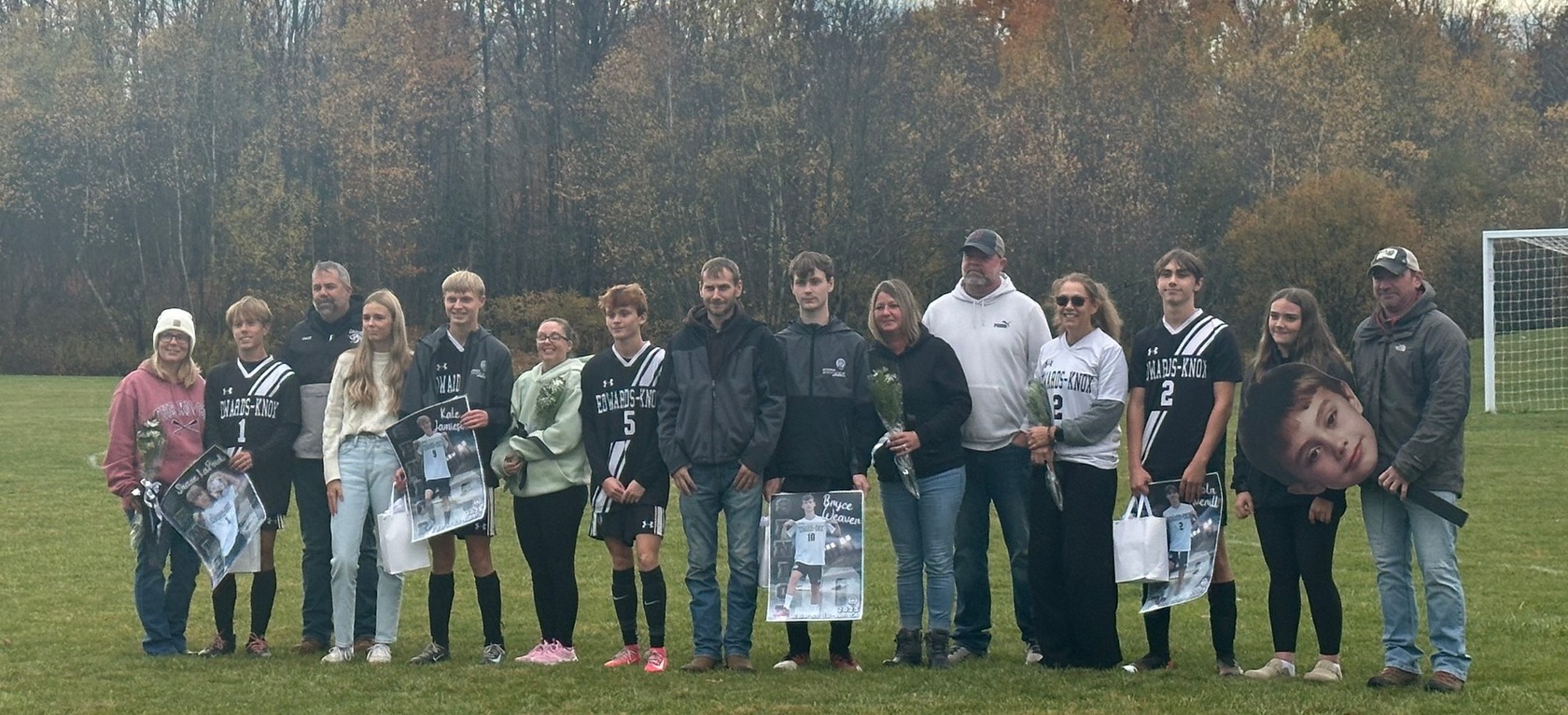 Small group of boys varsity soccer players with their families holding signs