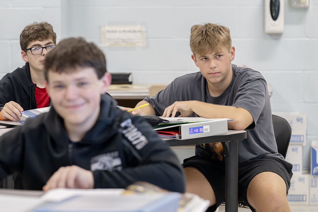 Students sit at their desks in a classroom.