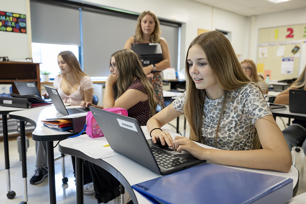 Students in a classroom work on laptops.