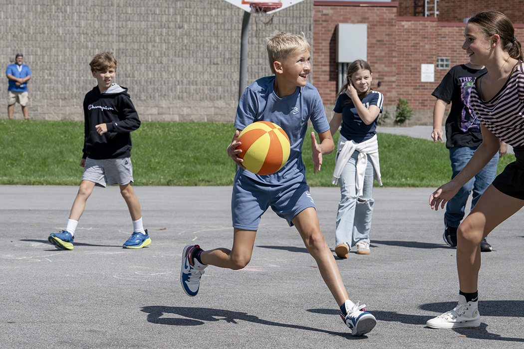 A student dribbles a basketball outside.